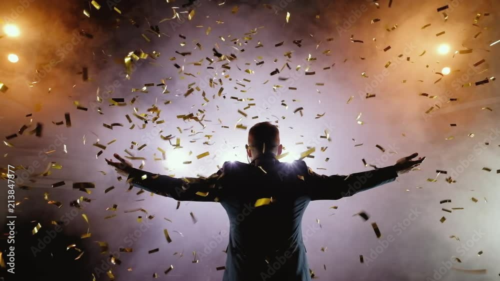 Successful businessman with arms up celebrating his victory. Celebrating success. Low angle view of excited young businessman keeping arms raised and expressing positivity while stands on the stage in