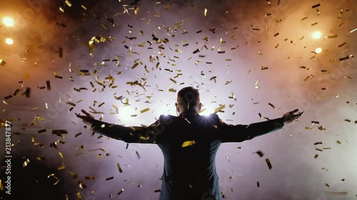 Successful businessman with arms up celebrating his victory. Celebrating success. Low angle view of excited young businessman keeping arms raised and expressing positivity while stands on the stage in