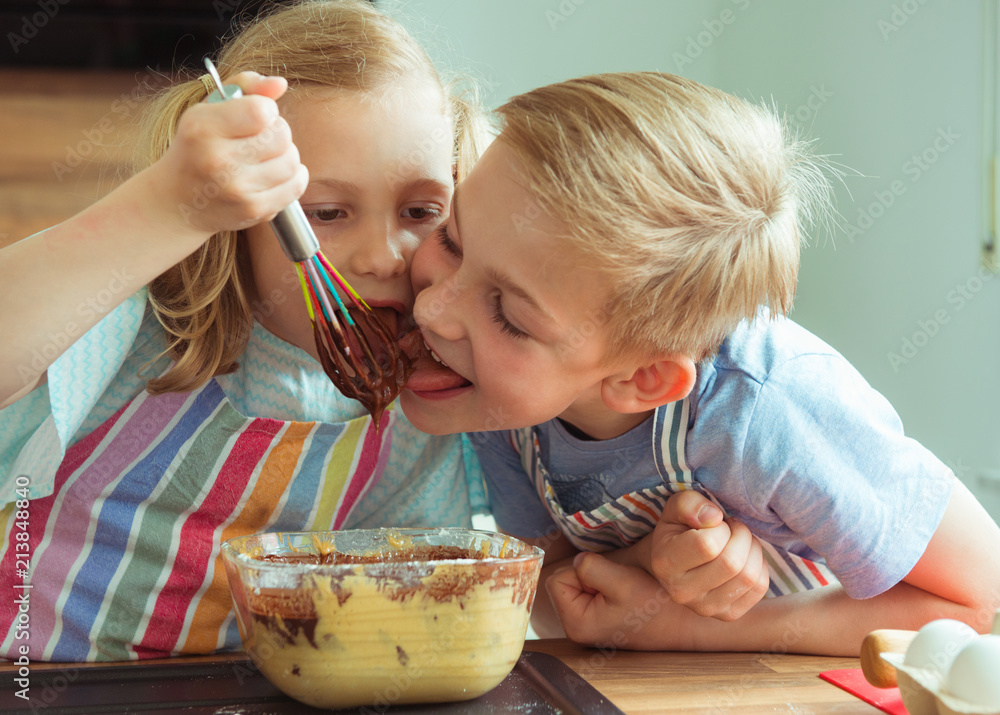 Two happy children having fun and taste chocolate in the modern kitchen during baking muffins Two happy children having fun and taste chocolate in the modern kitchen during baking muffins
