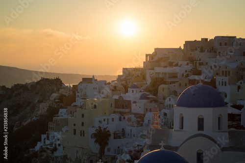 Whitewashed Houses and Church on Cliffs with Sea View and Sunset in Oia, Santorini, Cyclades, Greece