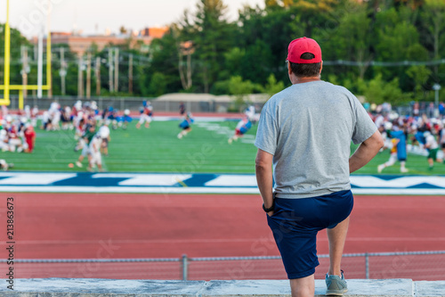 A standing man is watching a football game