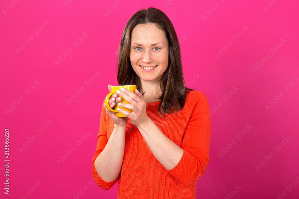 Beautiful brunette woman with a cup in hands on a pink background. Drink hot drinks and be healthy. Beautiful brunette woman with a cup in hands on a pink background. Drink hot drinks and be healthy.