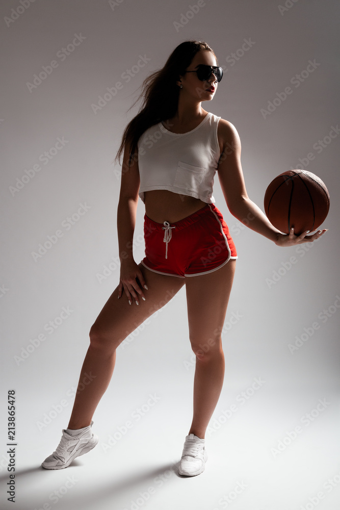 Sexy young lady in red shorts and white top, stay in studio with basketball.  Girl with long legs. Happy sporty women Stock Photo | Adobe Stock