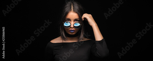 Foto Portrait of cool crazy brunette fashionable girl in sunglasses, casual hairdo on black background