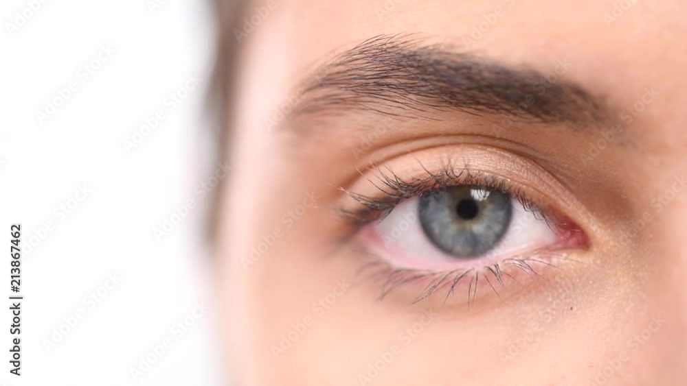 Beautiful female blue eye closeup. Young woman eye blinking and looking up, over white background. 4K UHD video 3840X2160