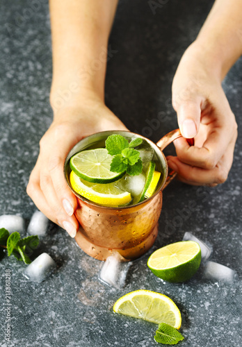 Woman's hands  holding a copper mug of lemonade with mint