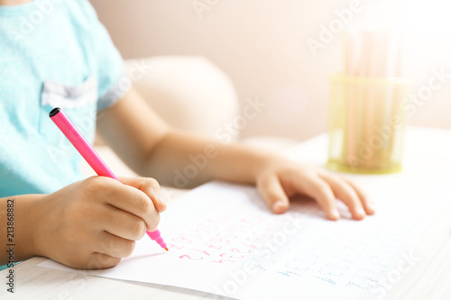 Schoolkid learns to write on sheet of paper  closeup