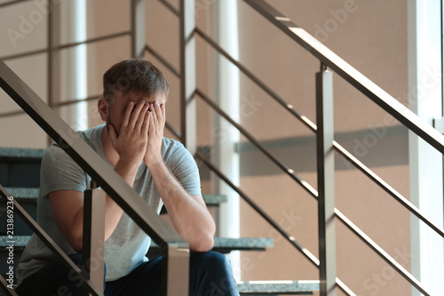 Depressed young man sitting on stairs