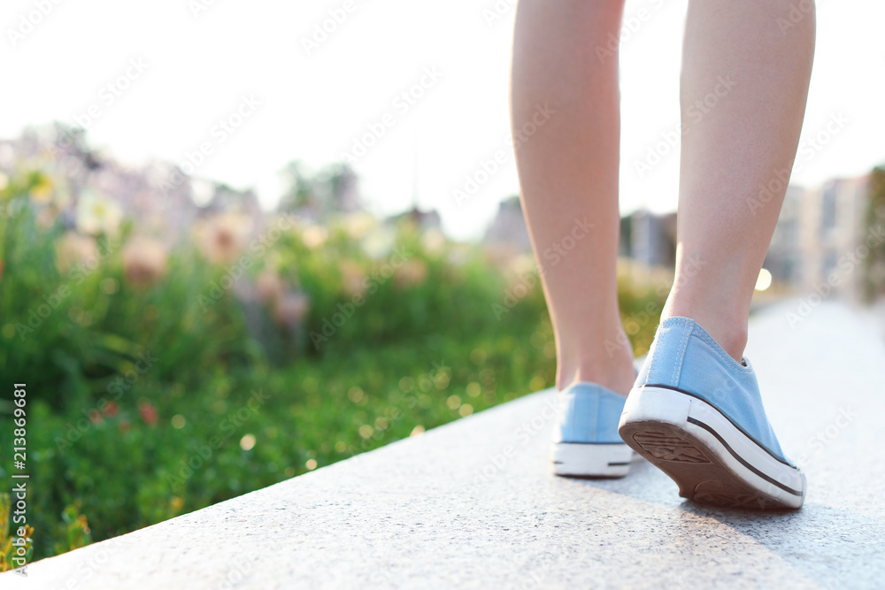 Woman in stylish sneakers walking outdoors, closeup. Urban fashion Woman in stylish sneakers walking outdoors, closeup. Urban fashion