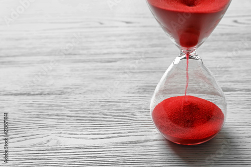 фотографія Hourglass with flowing red sand on wooden background