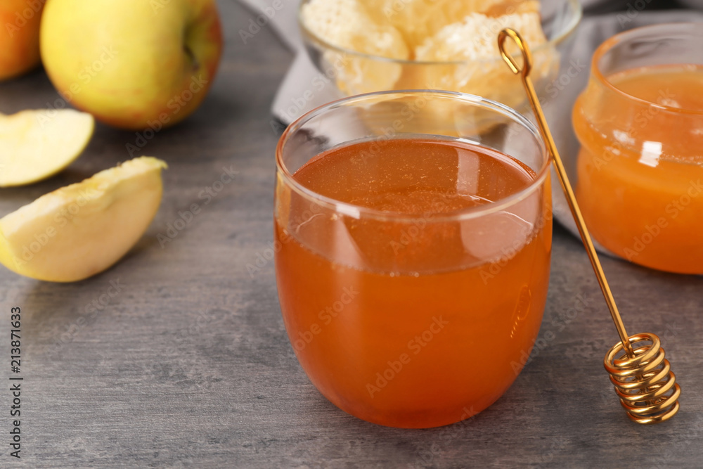 Glass of honey, apples and dipper on dark table Glass of honey, apples and dipper on dark table