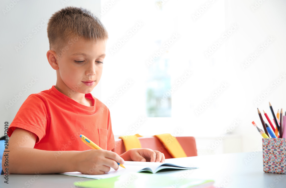 Cute little child doing assignment at desk in classroom. Elementary school Cute little child doing assignment at desk in classroom. Elementary school