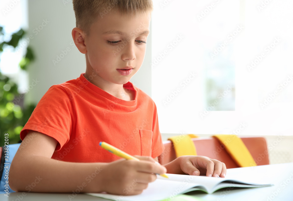 Cute little child doing assignment at desk in classroom. Elementary school Cute little child doing assignment at desk in classroom. Elementary school