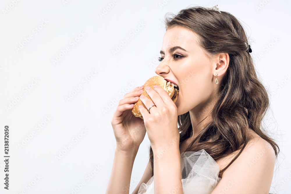 close-up portrait of hungry young bride in wedding dress eating hamburger isolated on white close-up portrait of hungry young bride in wedding dress eating hamburger isolated on white
