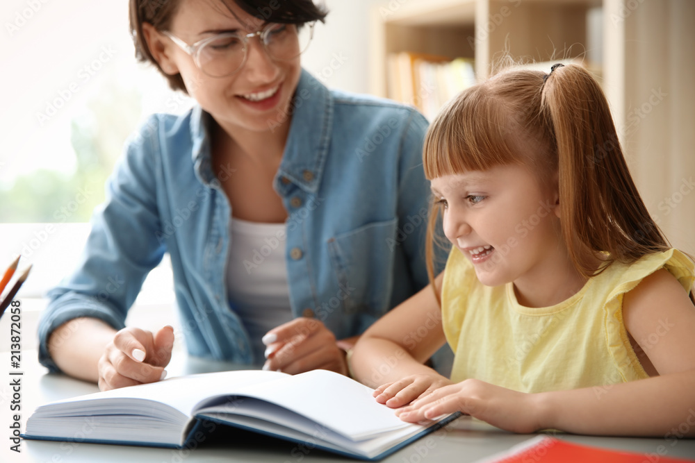 Female teacher helping child with assignment at school Female teacher helping child with assignment at school