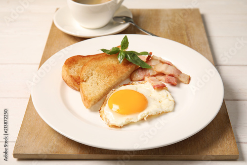 Fried egg with bacon and toasted bread on plate served for breakfast