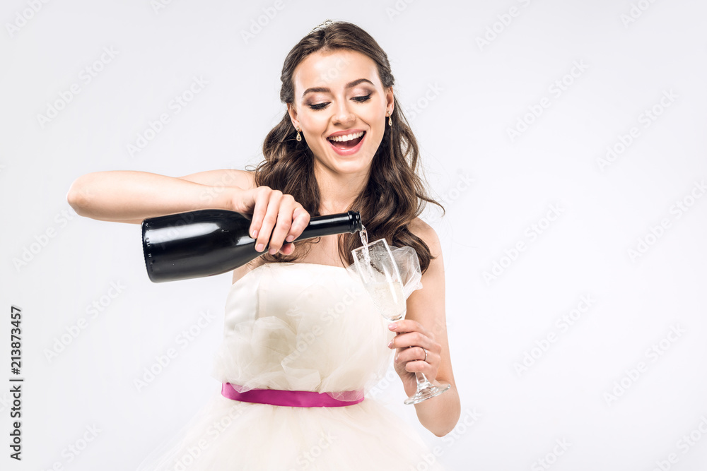 young bride in wedding dress pouring champagne into glass isolated on white young bride in wedding dress pouring champagne into glass isolated on white
