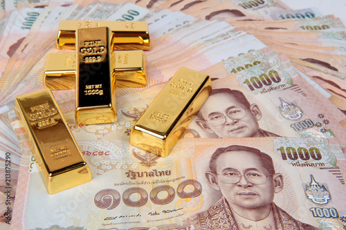 5 of 1 kg. Gold bar on 1000 Baht of Thailand banknotes nested a pile high.
