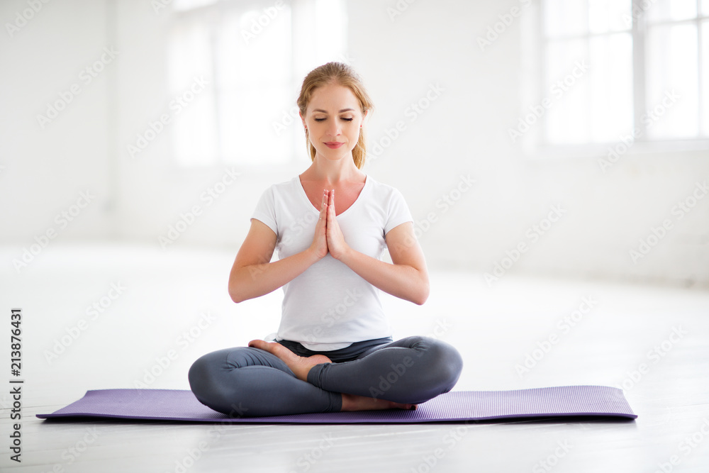woman practicing yoga and meditating in lotus position - obrazy, fototapety, plakaty 