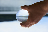 hand holding a glass ball with beach view. Upside down. Selective focus