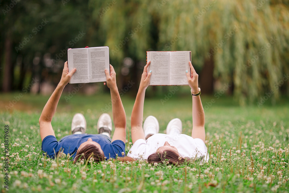 Relaxed young couple reading books while lying on grass
