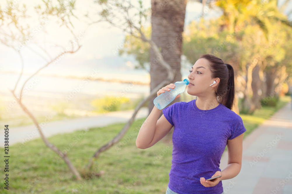 Young girl drinking water during morning jogging Young girl drinking water during morning jogging