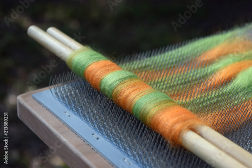 Colorful wool fiber on a blending board making a rolag on two wooden dowels photo