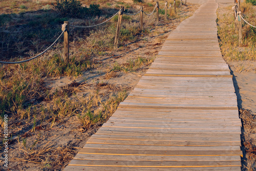 Fototapeta Naklejka Na Ścianę i Meble -  wooden path through the dunes towards a summer beach at sunset