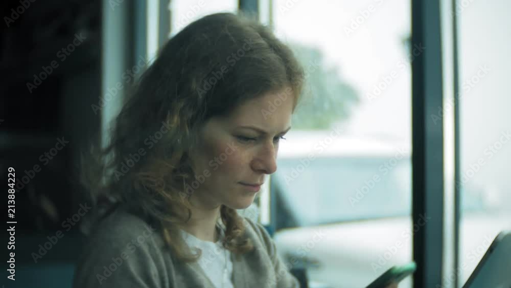 Young woman uses a tablet and phone, drinks tea in a cafe bar Young woman uses a tablet and phone, drinks tea in a cafe bar