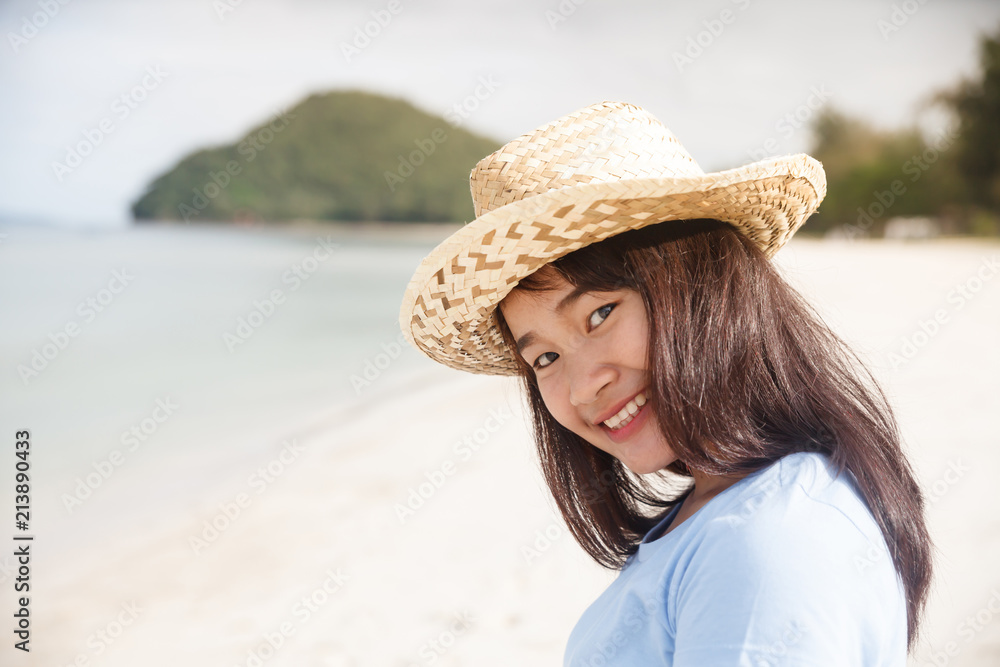 Smiling woman with straw hat at the beach.