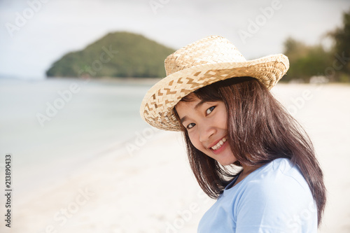 Smiling woman with straw hat at the beach.