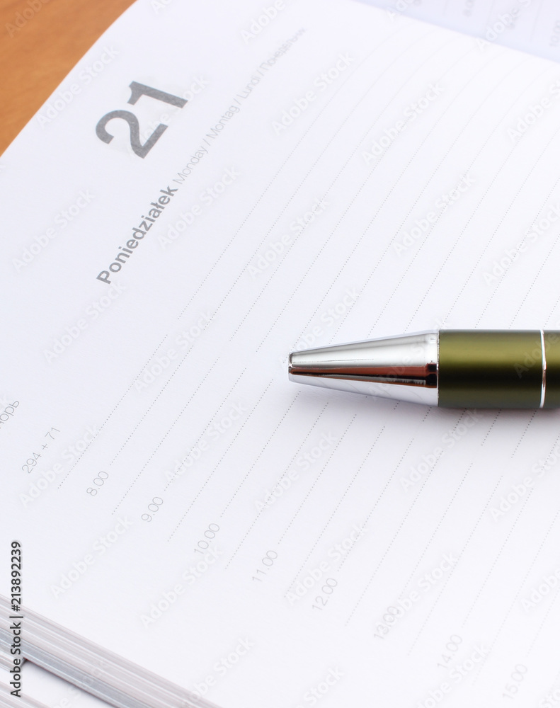 Pen lying on calendar or organizer on desk in office Pen lying on calendar or organizer on desk in office