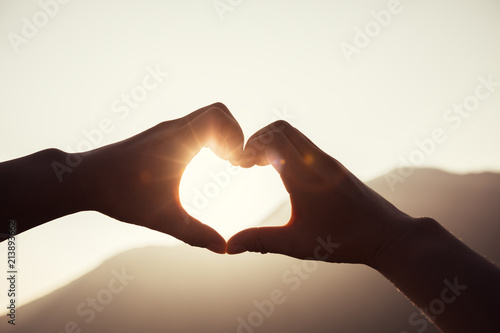 Hands making a Heart shape on Sunrise mountain top