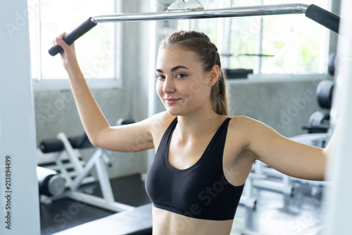 Muscular young woman with beautiful body doing exercises with dumbbell. Sporty girl lifting weights in gym.