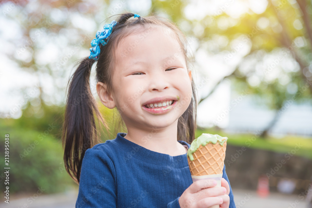 Little asian girl smiling with dirty mouth while eating ice cream in park Little asian girl smiling with dirty mouth while eating ice cream in park