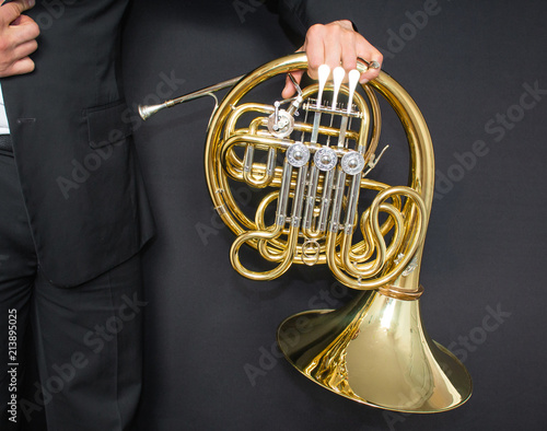 French horn player. Music instrument horn in the hands of hornist. A man in a suit  with a musical instrument. 