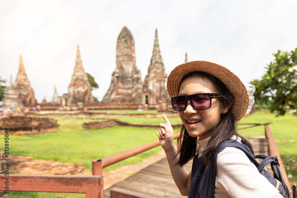 Cute happy smiling tourist girl,relaxing enjoying travelling at Wat Chaiwatthanaram is a Buddhist temple in the city of Ayutthaya Historical Park,Thailand, summer vacation,travel concept.