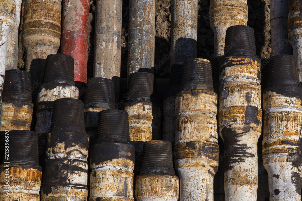 Fototapeta premium Oil Drill pipe. Rusty drill pipes were drilled in the well section. Downhole drilling rig. Laying the pipe on the deck. View of the shell of drill pipes laid in courtyard of the oil and gas warehouse.
