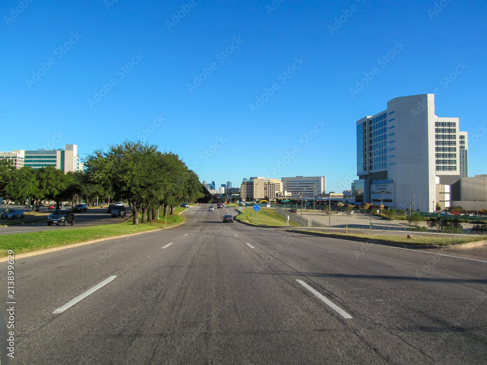 Direct road to Dallas. Beautiful view of city asphalt street on sunny day against a blue sky. Skyline of urban scene.