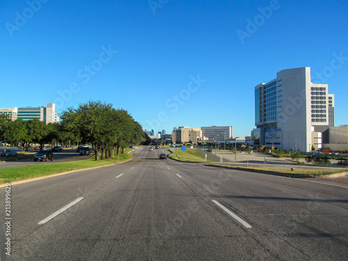 Direct road to Dallas. Beautiful view of city asphalt street on sunny day against a blue sky. Skyline of urban scene.