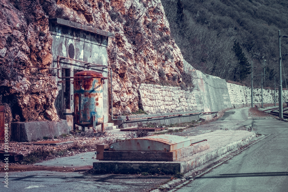 Panoramic side view of old rusted metal tank and underground tank in abandoned industrial area.