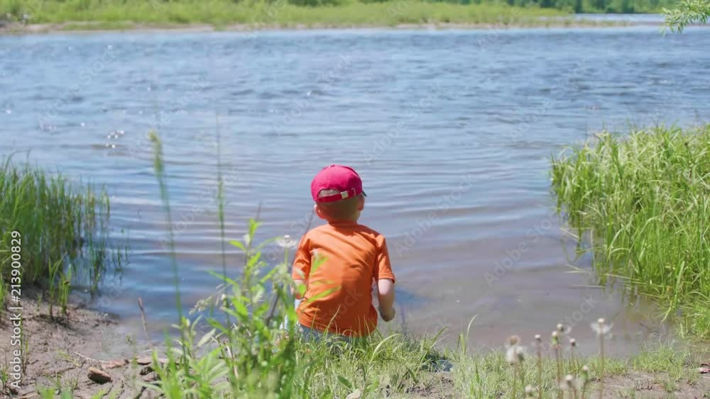 Boy fishing net on the river Bank. Beautiful summer landscape. Outdoor recreation. Summer holidays in the village Boy fishing net on the river Bank. Beautiful summer landscape. Outdoor recreation. Summer holidays in the village