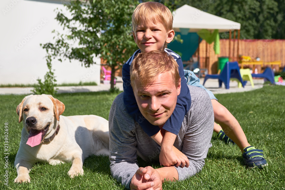 Obraz premium Happy family on the grass with a wonderful labrador