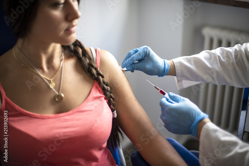 medico disinfetta la pelle di una paziente prima di fare una vaccinazione