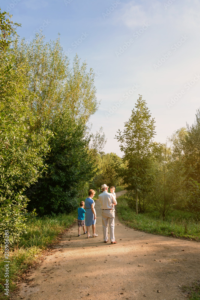 Back view of grandparents and grandchildren walking on a nature path