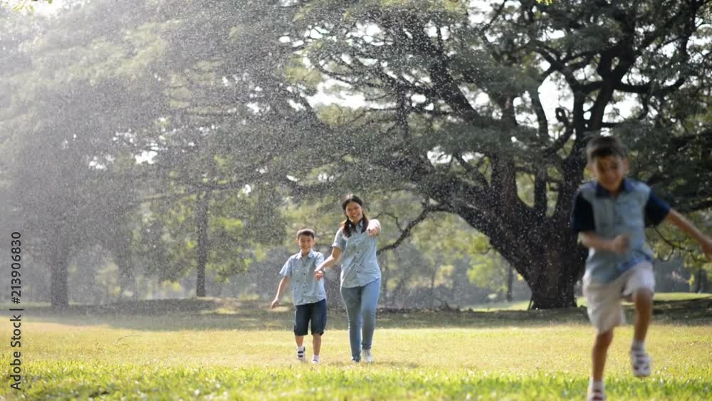 Single mother taking sons hand running in the park with rain Single mother taking sons hand running in the park with rain