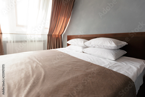 Bed maid-up with clean white pillows and bed sheets in beauty room.