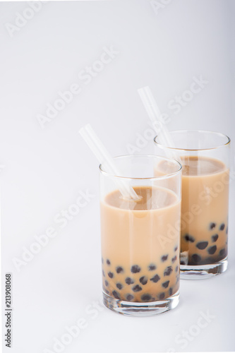 A glass of sweet milk bubble tea with tapioca pearls, and straw on white background. Copy space