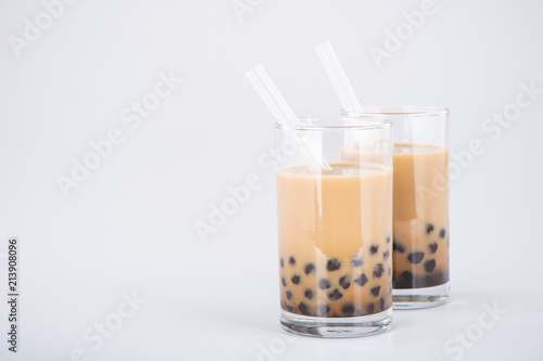 A glass of sweet milk bubble tea with tapioca pearls, and straw on white background. Copy space