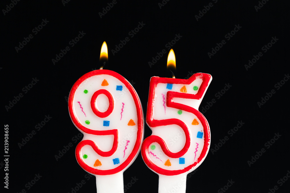 Colorful burning birthday candle on dark background Colorful burning birthday candle on dark background